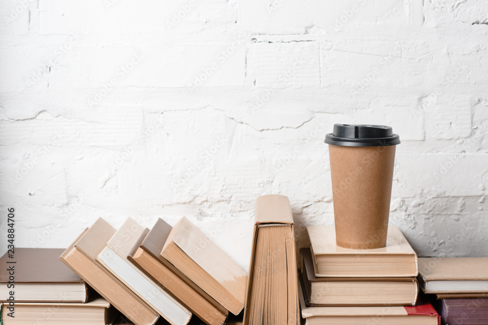 books with hardcovers and coffee to go near white brick wall books with hardcovers and coffee to go near white brick wall