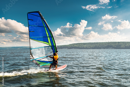 the man athlete rides the windsurf over the waves on lake photo