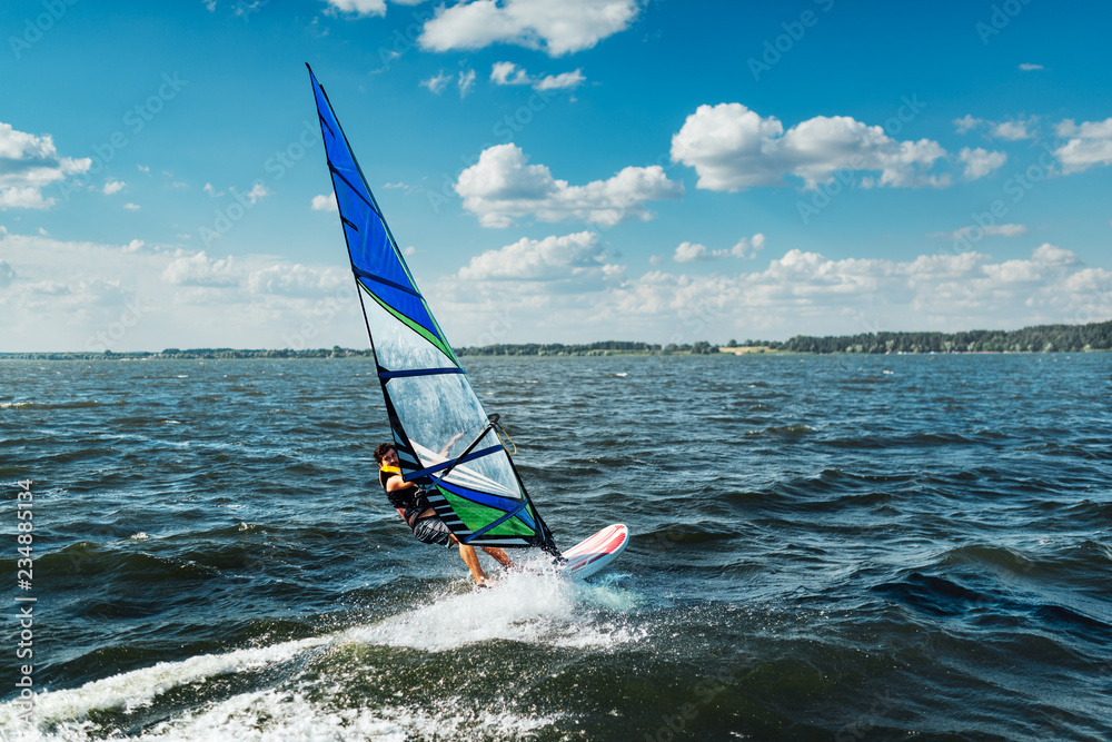 Naklejka premium the man athlete rides the windsurf over the waves on lake