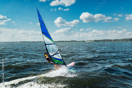 the man athlete rides the windsurf over the waves on lake