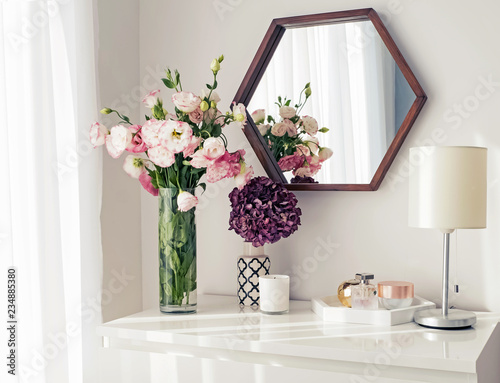 Light room with mirrow, flowers, night lamp and other objects photo