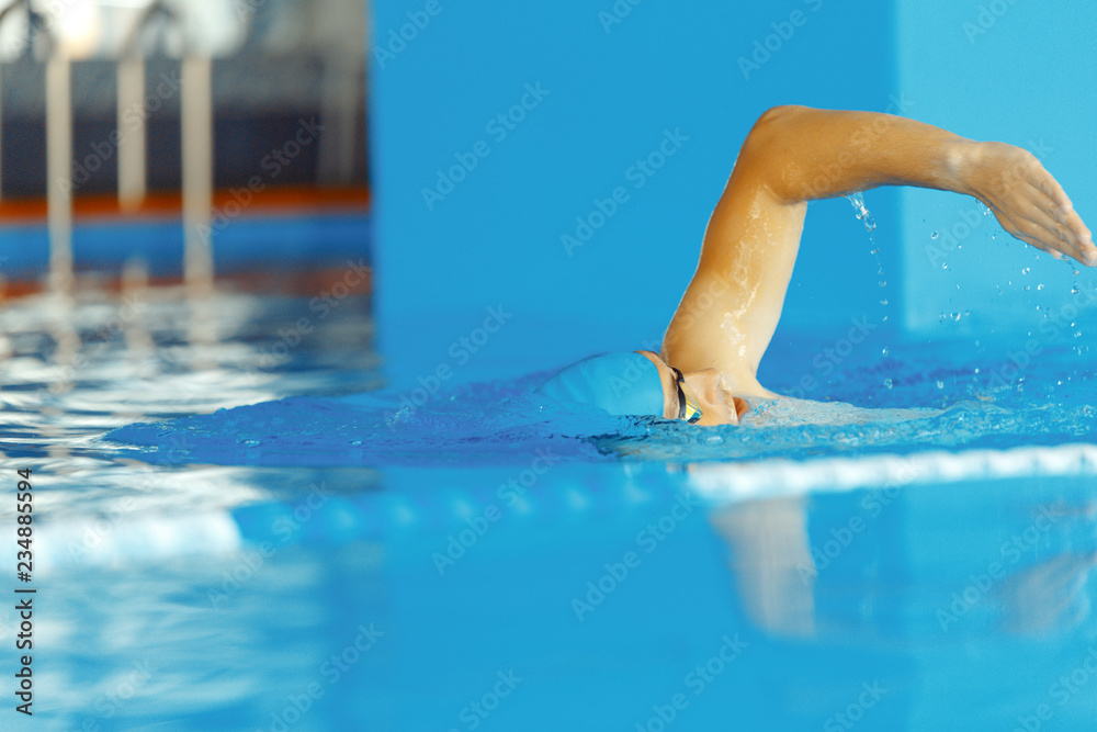Image of young athlete man in blue cap swimming in pool