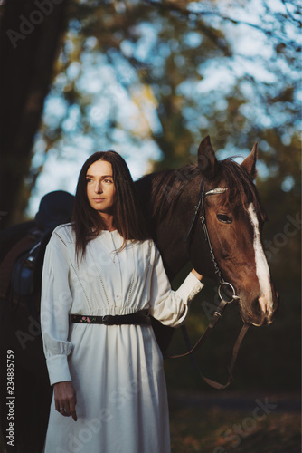 Charming woman standing with her horse in autumn park