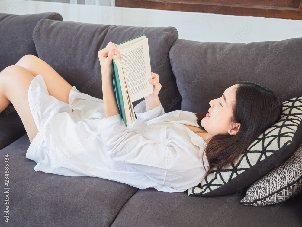 Obraz premium asian woman sitting and read book on sofa at home