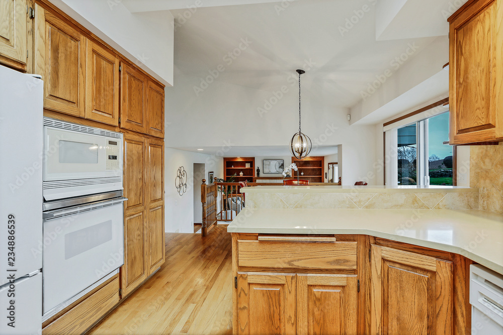 Fototapeta premium Open large kitchen interior with vaulted ceiling and white appliances.