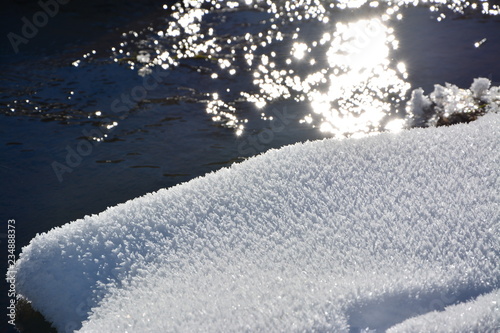 Snowy crystals in the sun with water in the background © Phillip