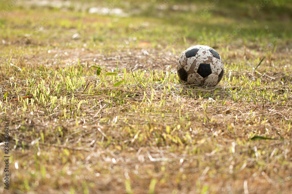 The Old soccer ball on grass worse, Poor soccer game field at countryside The Old soccer ball on grass worse, Poor soccer game field at countryside