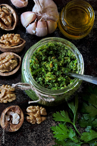 Walnut pesto with parsley. Homemade pesto sauce in a jar. Top view. Vegan pesto with walnut and parsley.