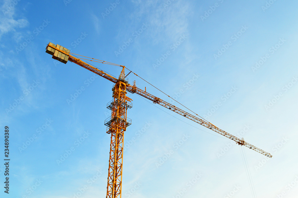 big crane / The yellow huge crane on blue sky background - construction crane working in the construction site big crane / The yellow huge crane on blue sky background - construction crane working in the construction site
