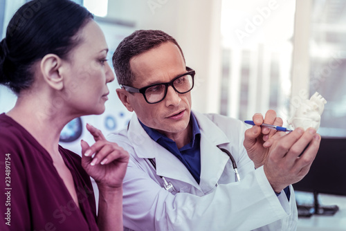 Close up of competent doctor that staring at artificial organ photo