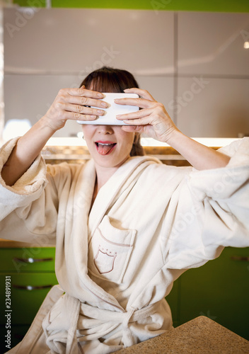 Beautiful young girl in the chic kitchen at breakfast reads a newspaper and takes a selfie for social networks