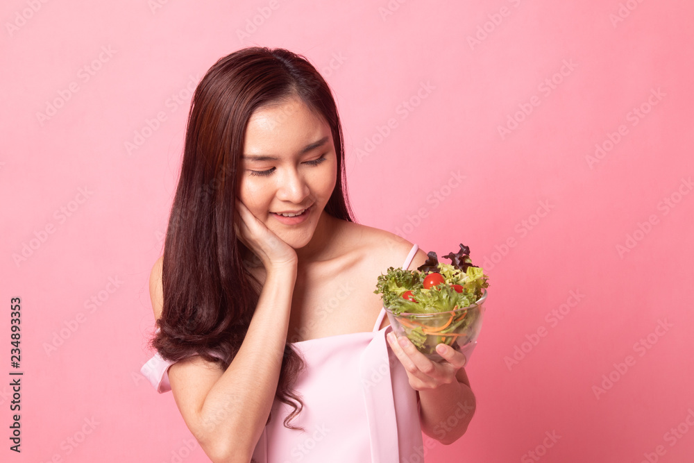 Healthy Asian woman with salad on pink background Healthy Asian woman with salad on pink background