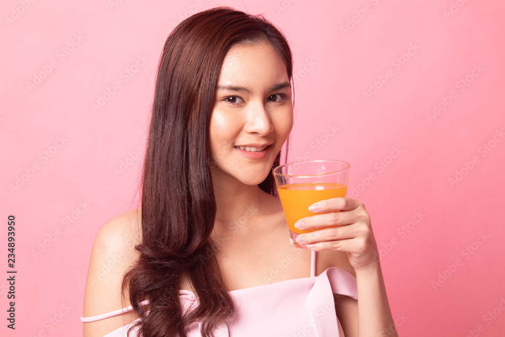 Healthy young Asian woman with orange juice on pink background Healthy young Asian woman with orange juice on pink background
