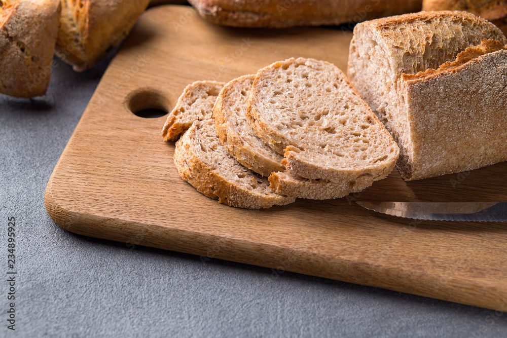 Sliced bread on the grey stone table, knife, close up. Sliced bread on the grey stone table, knife, close up.