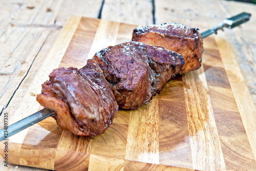 Cooked Picanha skewer ready to eat leaning on chopping board