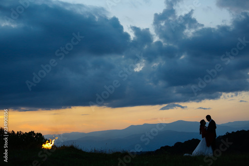 Beautiful wedding couple posing in nature with fire