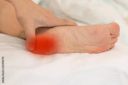 Heel Pain or plantar fasciitis concept. Hand on foot as suffer from inflammation feet problem of Sever's Disease or calcaneal apophysitis. photo