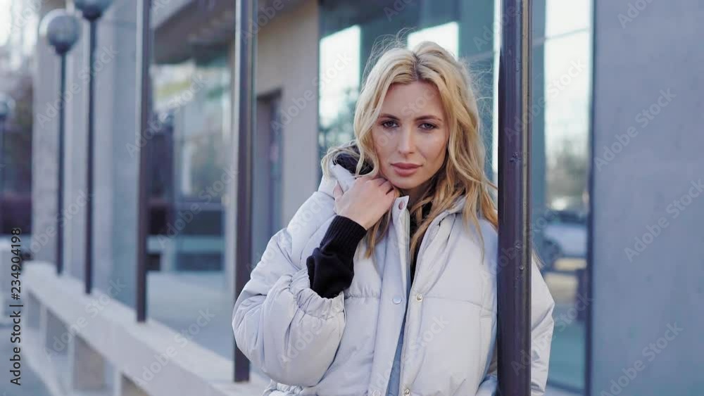 Beautiful woman on the city street. Portrait of a young blonde in a down jacket Beautiful woman on the city street. Portrait of a young blonde in a down jacket