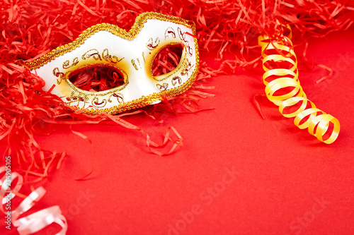 Yellow and white carnival mask on red background.