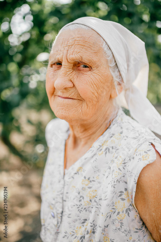 Elderly happy woman outdoor portrait.  Old  odd lady with wrinkled skin face looking at camera.  Detailed aged face skin. Great grandmother face expression. Senior grannie female. Country lifestyle. photo