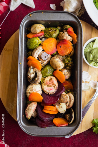 Hot baked, roasted, grilled vegetables in metal baking form. Beetroot, carrot, mushrooms, pumpkin, brussels sprouts with avocado dip sauce. Vegan red Christmas lunch, vegetarian dinner, healthy food