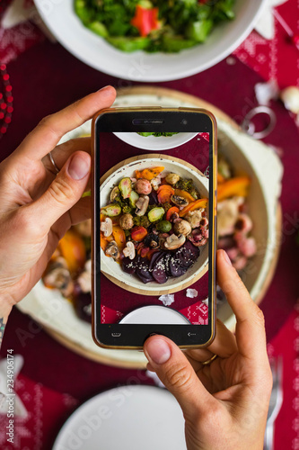 Phone food photography. Woman hands take a photo of lunch or dinner with smartphone for social networks or blogging in trendy top view style. Mobile phone screen. Vegan vegetarian healthy food