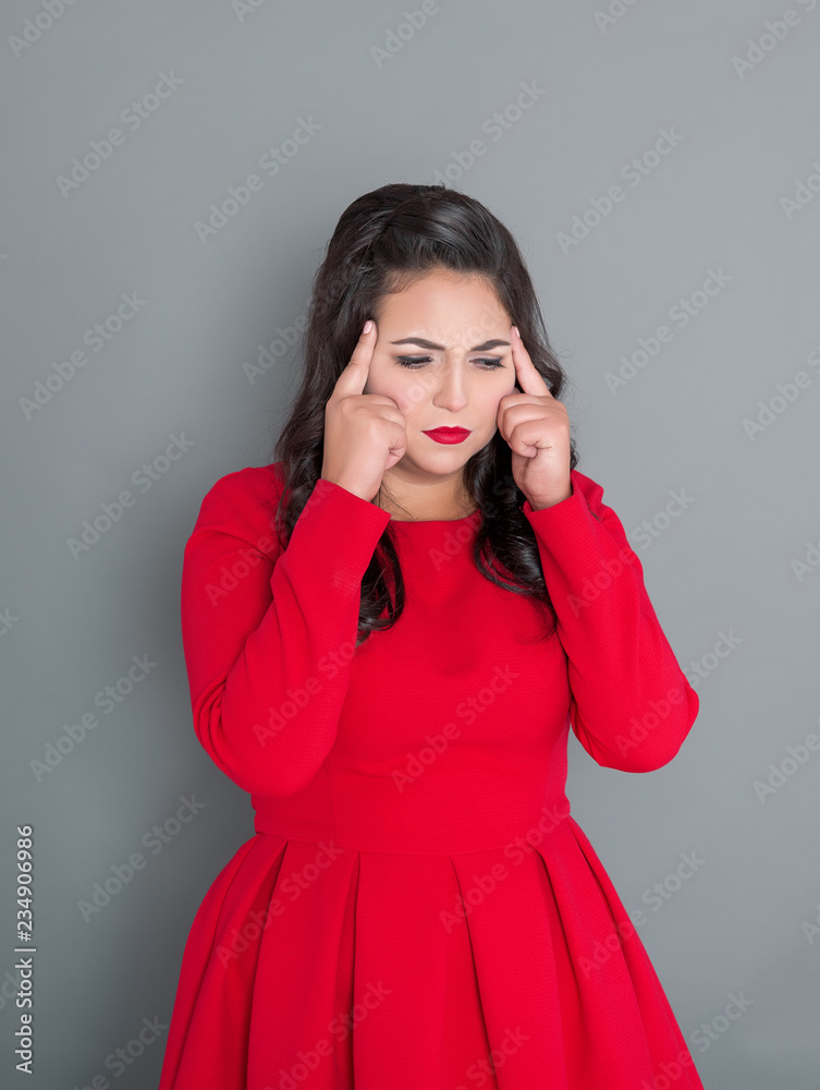 Plus size woman in red dress with headache on gray Plus size woman in red dress with headache on gray