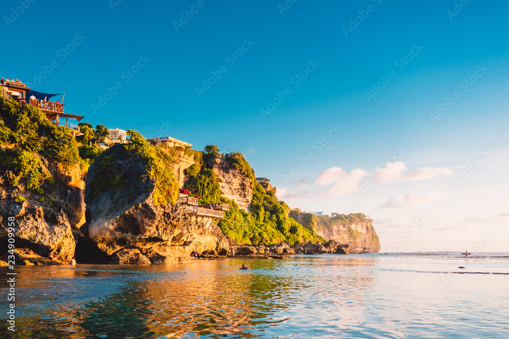 Blue sky, ocean and rocky cliff in Uluwatu, Bali and sunset light