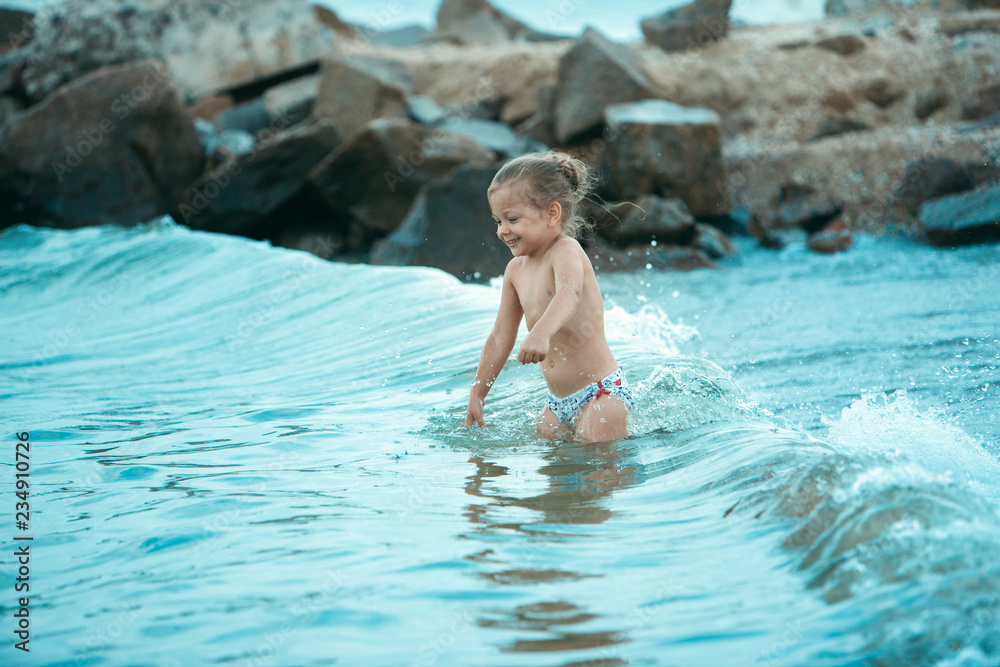 The happy child girl playing on the sea beach at the sunny day time. The summer, childhood, holiday, leisure, lifestyle, travel, vacation concept The happy child girl playing on the sea beach at the sunny day time. The summer, childhood, holiday, leisure, lifestyle, travel, vacation concept