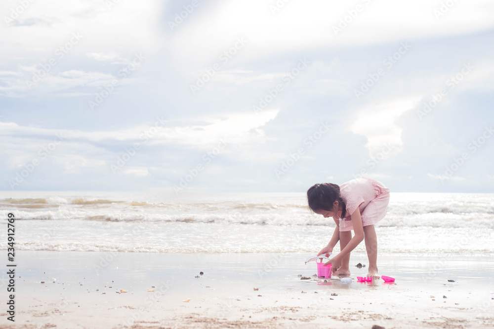 Asian child girl playing with toys on the beach