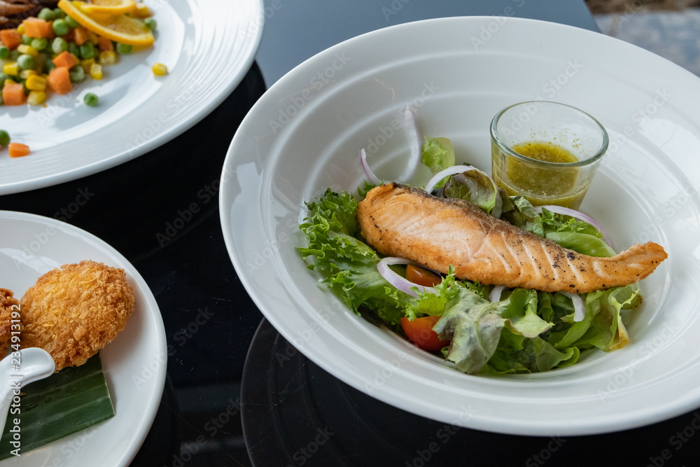 Grilled salmon on top of fresh salad, Concept of healthy food. Salad with green leaves and boiled salmon. Food photography. Fresh foods Grilled salmon on top of fresh salad, Concept of healthy food. Salad with green leaves and boiled salmon. Food photography. Fresh foods
