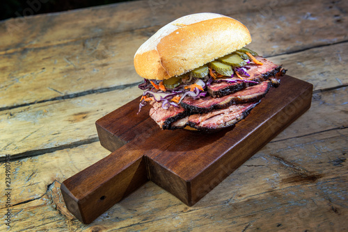 Brisket Sandwich with cucumber and coleslow on cutting board
