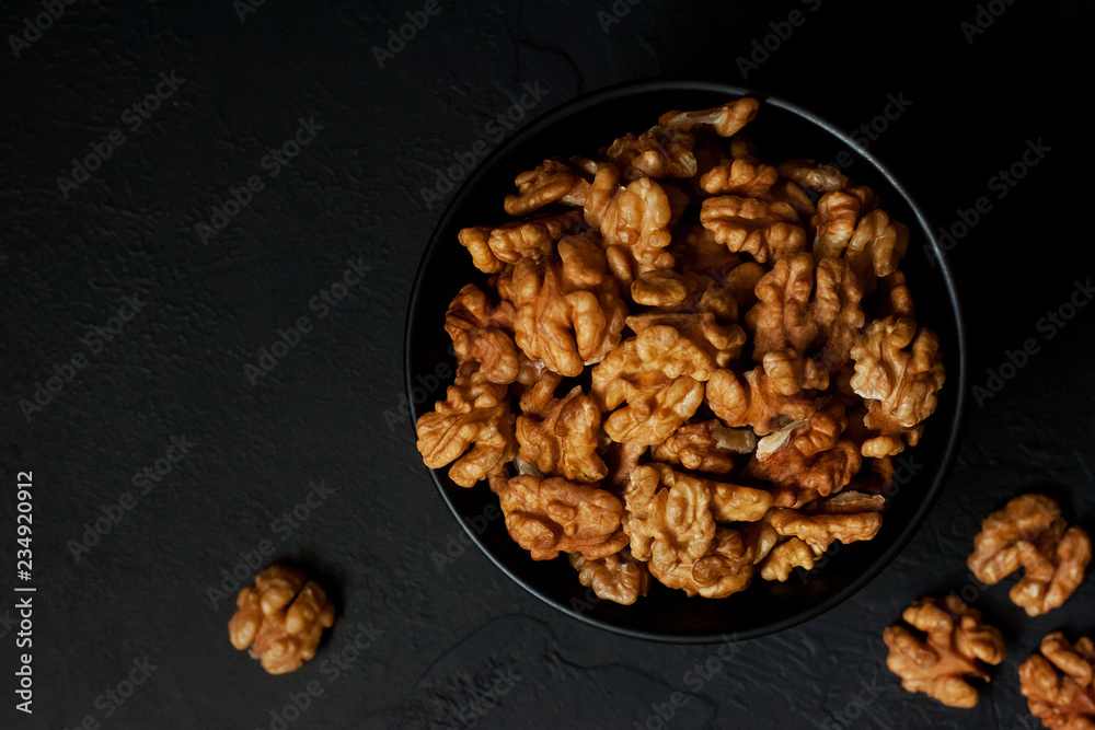 Obraz premium Walnut in a bowl on a black slate or stone background - healthy snack.Top view with copy space.