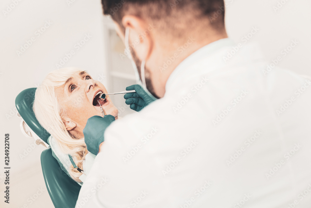 Senior lady with open mouth sitting in dental chair