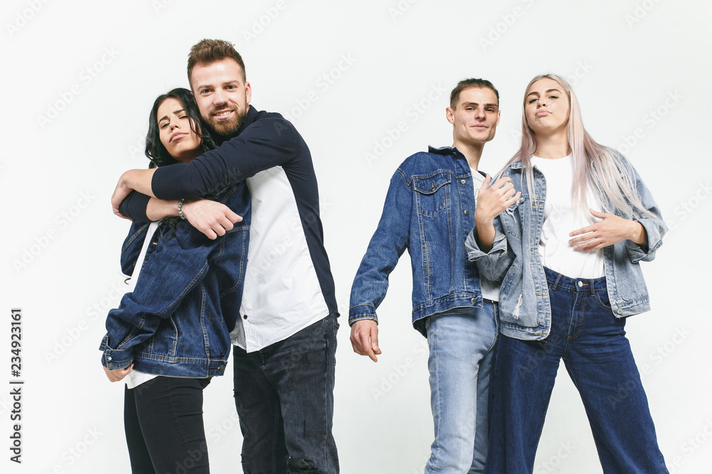 Fototapeta premium Group of smiling friends in fashionable jeans. The young men and woman posing at studio. The fashion, people, happy, lifestyle, clothes concept