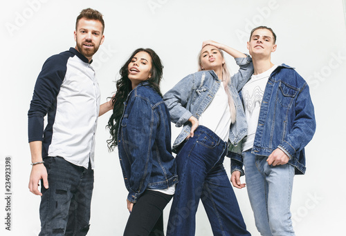 Group of smiling friends in fashionable jeans. The young men and woman posing at studio. The fashion, people, happy, lifestyle, clothes concept