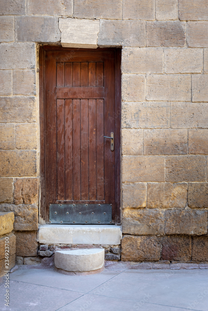 Old wooden door framed by bricks stone wall at the courtyard of al Razzaz historic house, Darb al Ahmar district, Old Cairo, Egypt Old wooden door framed by bricks stone wall at the courtyard of al Razzaz historic house, Darb al Ahmar district, Old Cairo, Egypt