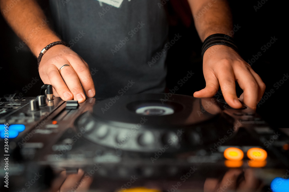 Dj mixes the track in the nightclub at party. In the background laser light show