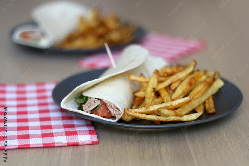 Tortilla wraps with tuna and various vegetables and french fries. Selective focus. Tortilla wraps with tuna and various vegetables and french fries. Selective focus.