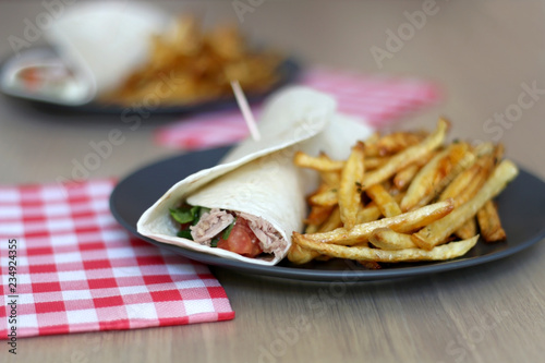 Tortilla wraps with tuna and various vegetables and french fries. Selective focus.