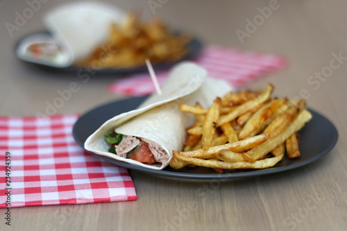 Tortilla wraps with tuna and various vegetables and french fries. Selective focus.