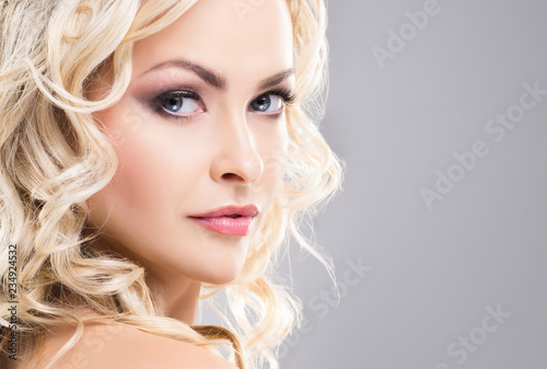 Portrait of young and beautiful blond girl with curly hair. Face lifting and beauty concept.