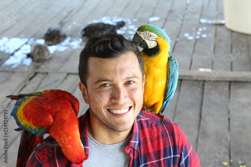 Handsome tourist interacting with macaws visiting Peru