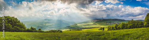 Lichteinfall auf einer grünen Wiese mit Wolken - Panorama 