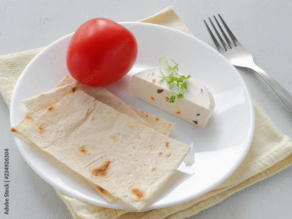 Close up of Mediterranean breakfast with soft cheese, vegetables and grocery served with fresh pita bread. Healthy breakfast. Selective focus on the center.