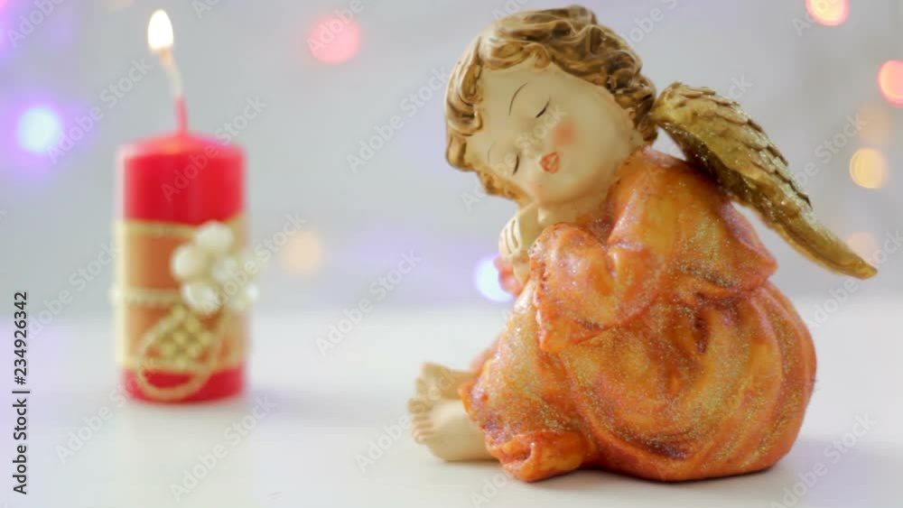 Hand lights a red candle with sweet angel in the front Hand lights a red candle with sweet angel in the front