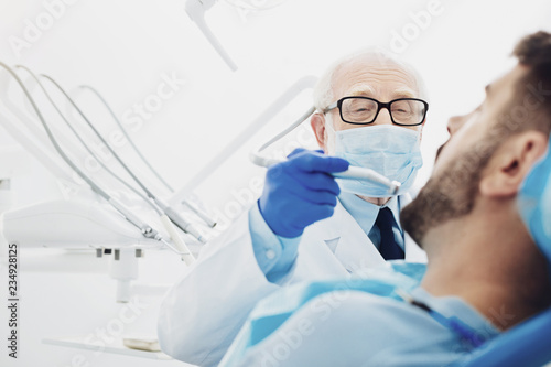 Experienced male dentist replacing tooth