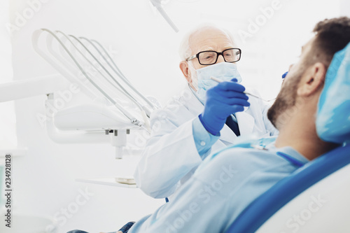 Professional male dentist diagnosing patient