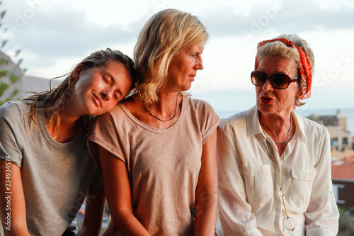 Three generations of attractive women of a family together on summer terrace. Authentic, unadorned, unplugged.
