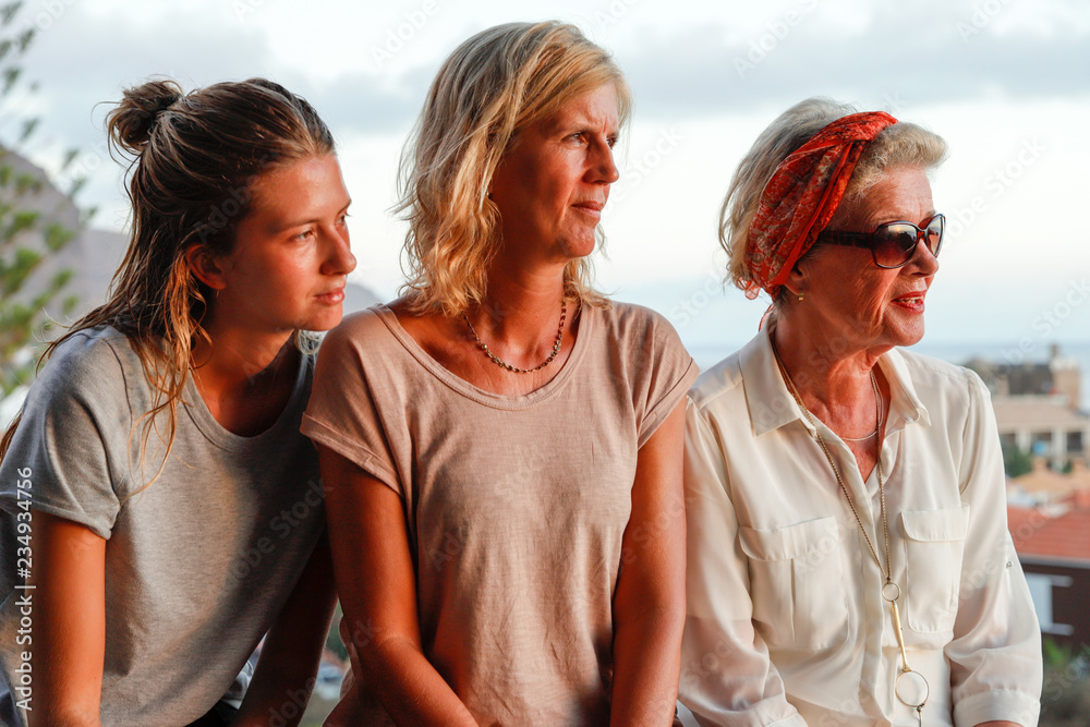 Three generations of attractive women of a family together on summer terrace. Authentic, unadorned, unplugged.